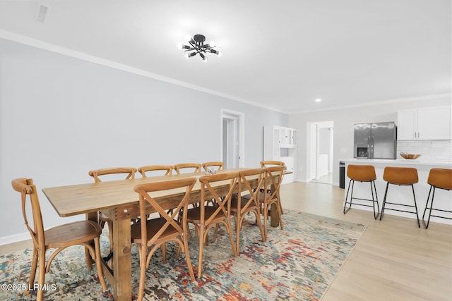 dining room featuring light wood-type flooring, ornamental molding, and recessed lighting