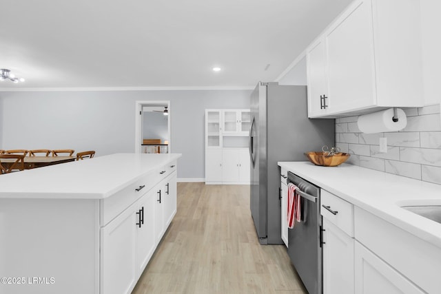 kitchen with stainless steel appliances, light wood-style floors, tasteful backsplash, light countertops, and white cabinets