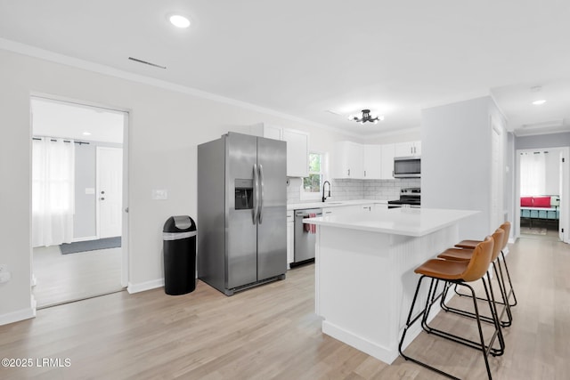 kitchen with light wood finished floors, backsplash, appliances with stainless steel finishes, and light countertops