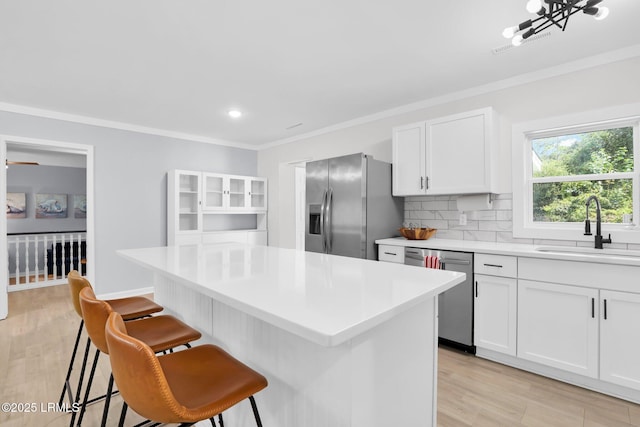 kitchen with a sink, decorative backsplash, a breakfast bar area, a kitchen island, and appliances with stainless steel finishes