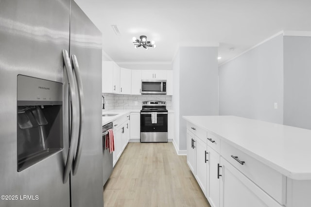kitchen featuring stainless steel appliances, light wood-style floors, light countertops, backsplash, and a sink