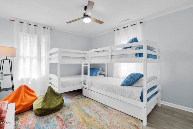 bedroom featuring multiple windows, ceiling fan, wood finished floors, and baseboards