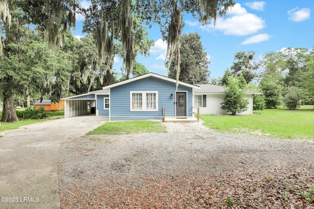 ranch-style home featuring concrete driveway, a carport, and a front yard