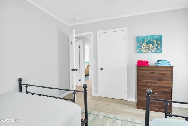 bedroom featuring wood finished floors, crown molding, and baseboards