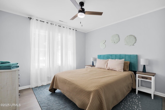 bedroom with a ceiling fan, visible vents, wood finished floors, and baseboards