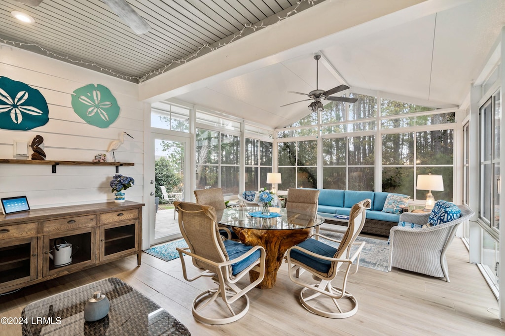 sunroom / solarium featuring ceiling fan, a healthy amount of sunlight, and vaulted ceiling with beams