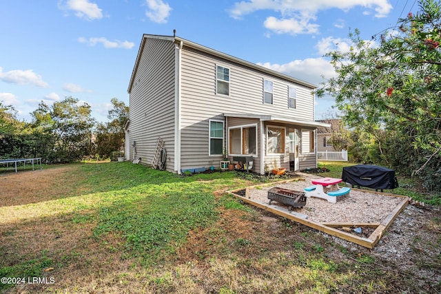 rear view of house featuring a trampoline and a lawn