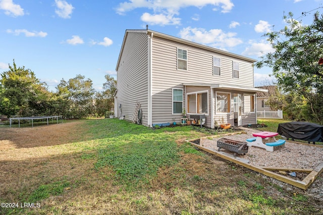 back of house featuring a trampoline and a yard