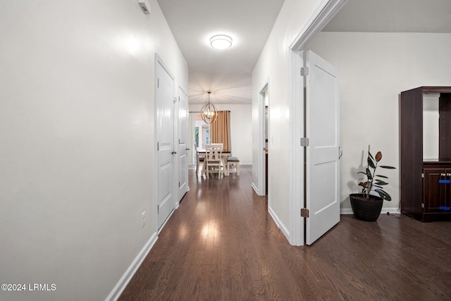 hall with dark hardwood / wood-style floors and a chandelier