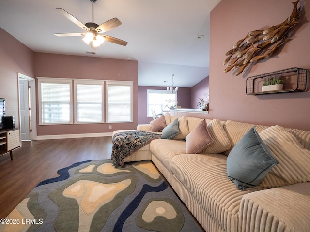 living area with baseboards, wood finished floors, and ceiling fan with notable chandelier