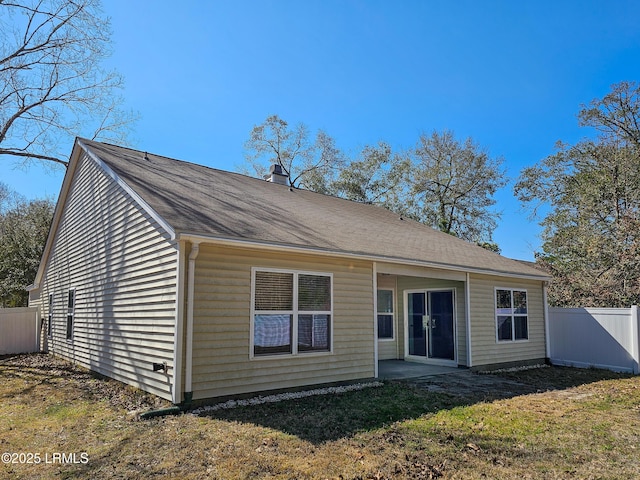 rear view of house with a yard, fence, a chimney, and a patio