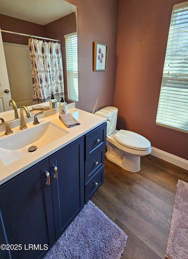 full bath with toilet, a shower with shower curtain, wood finished floors, vanity, and baseboards