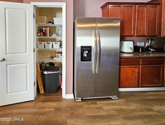 kitchen featuring dark wood-style floors, dark stone counters, and stainless steel fridge with ice dispenser