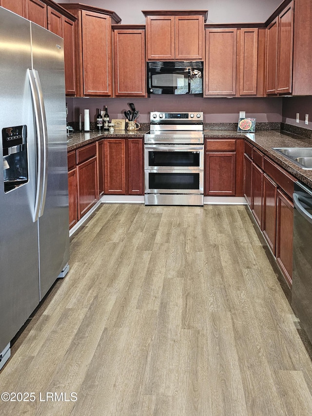 kitchen with light wood-type flooring, brown cabinets, stainless steel appliances, and a sink