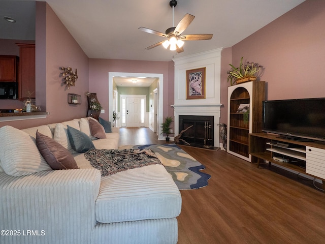 living area featuring a fireplace, wood finished floors, and a ceiling fan