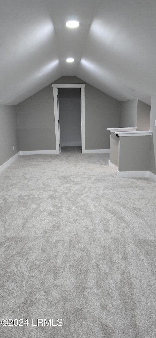 additional living space with lofted ceiling and light carpet