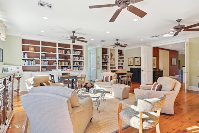 living room featuring built in shelves, ornamental molding, and light wood-type flooring