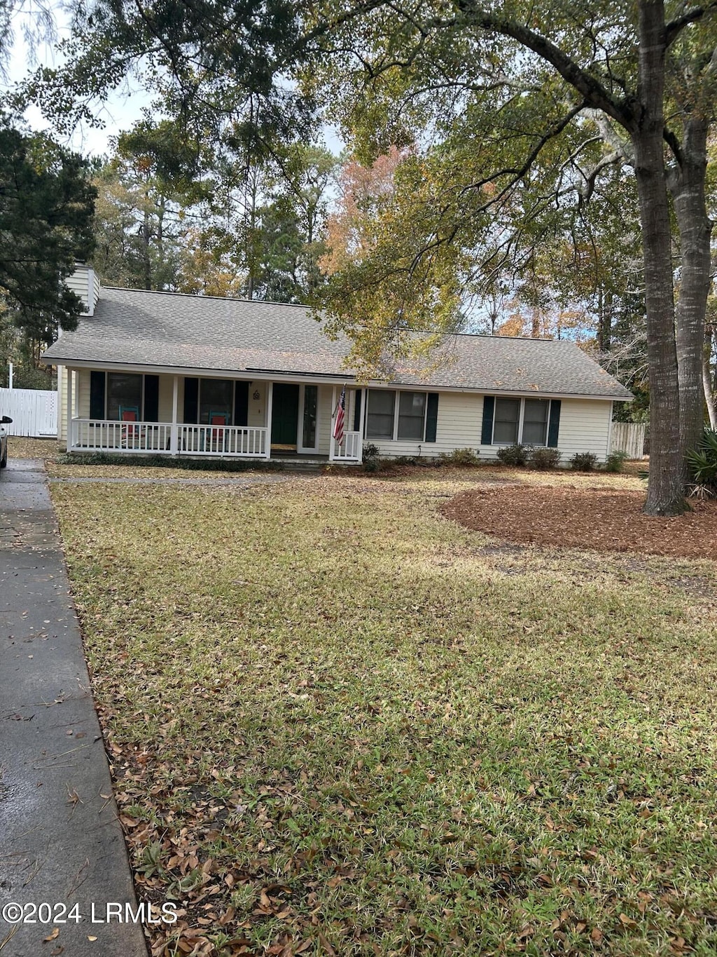 single story home featuring covered porch and a front lawn