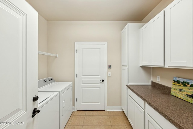 clothes washing area featuring light tile patterned flooring, cabinet space, baseboards, and washer and clothes dryer