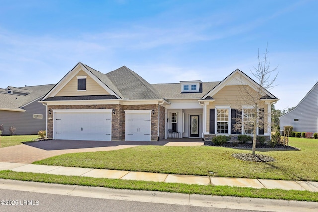 craftsman house with a front lawn, roof with shingles, concrete driveway, a garage, and brick siding