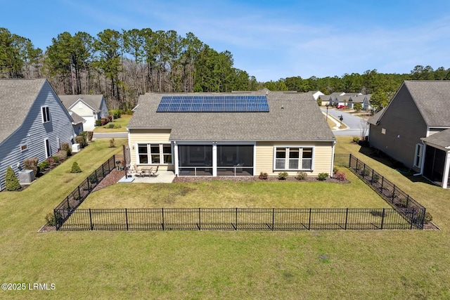 back of house featuring solar panels, a fenced backyard, a sunroom, a patio area, and a lawn