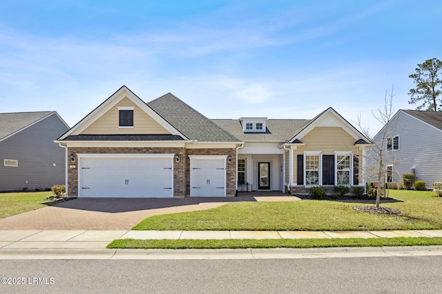 view of front facade with a front yard, an attached garage, a shingled roof, decorative driveway, and brick siding