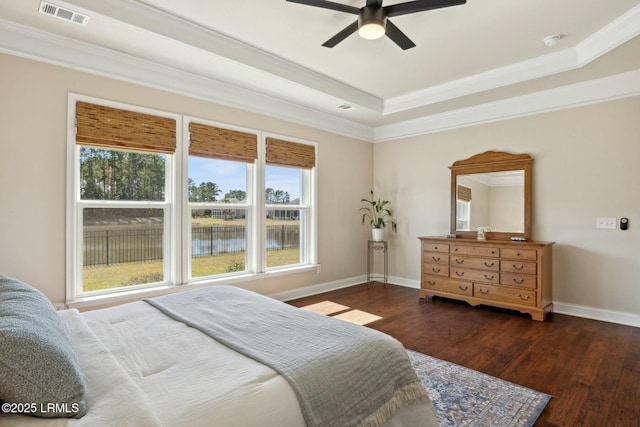 bedroom featuring visible vents, ornamental molding, wood finished floors, baseboards, and a raised ceiling