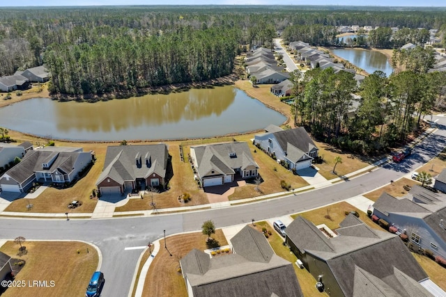 drone / aerial view with a wooded view, a water view, and a residential view