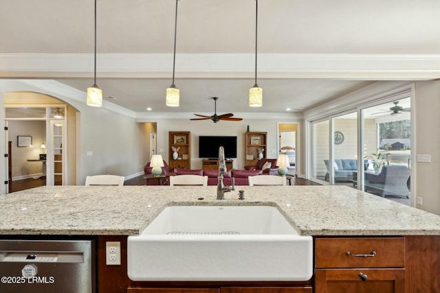 kitchen with a sink, open floor plan, ornamental molding, arched walkways, and stainless steel dishwasher