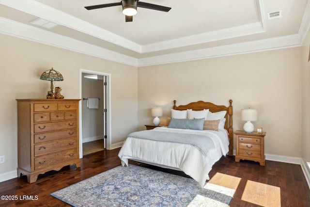 bedroom with a raised ceiling, wood finished floors, visible vents, and baseboards