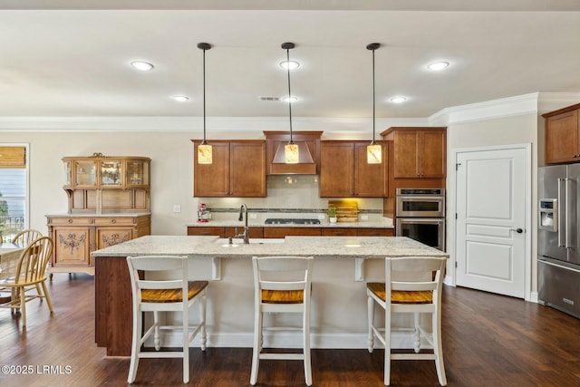 kitchen with custom range hood, brown cabinetry, and stainless steel appliances