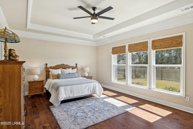 bedroom featuring visible vents, crown molding, baseboards, a tray ceiling, and hardwood / wood-style floors