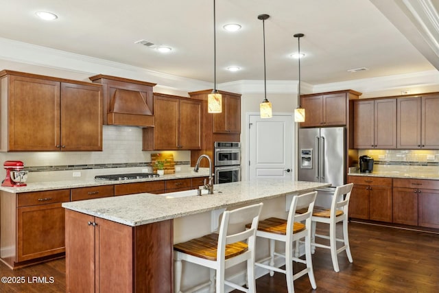 kitchen with a sink, dark wood-style floors, custom exhaust hood, stainless steel appliances, and a kitchen island with sink