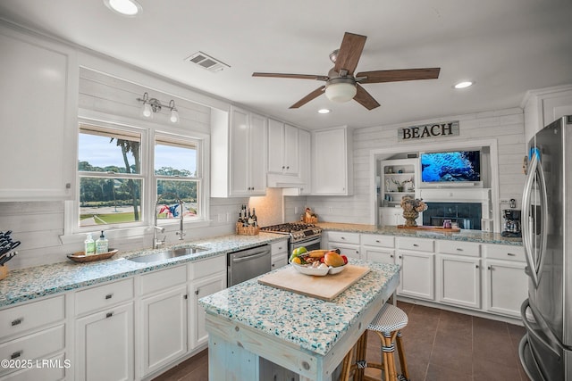 kitchen with visible vents, white cabinets, appliances with stainless steel finishes, light stone countertops, and a sink