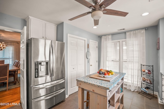 kitchen featuring visible vents, white cabinets, dark tile patterned flooring, light stone counters, and stainless steel refrigerator with ice dispenser