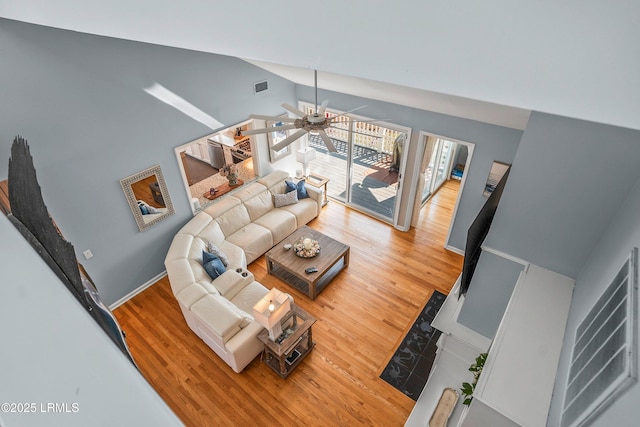 living room with ceiling fan, high vaulted ceiling, light wood-style flooring, visible vents, and baseboards