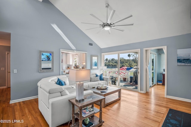 living area with light wood-style floors, ceiling fan, high vaulted ceiling, and baseboards