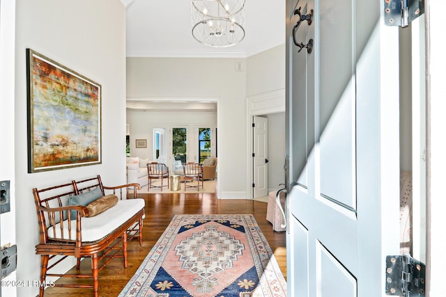 foyer with crown molding, dark wood-type flooring, and a notable chandelier