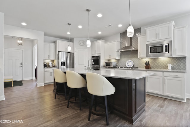 223 Rudder Run, Bluffton, SC 29910 - kitchen with appliances with stainless steel finishes, wall chimney range hood, tasteful backsplash, an island with sink, and wood finished floors