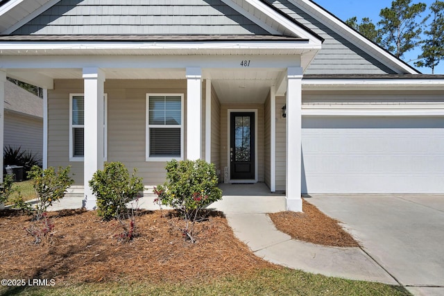 view of exterior entry featuring driveway and a garage