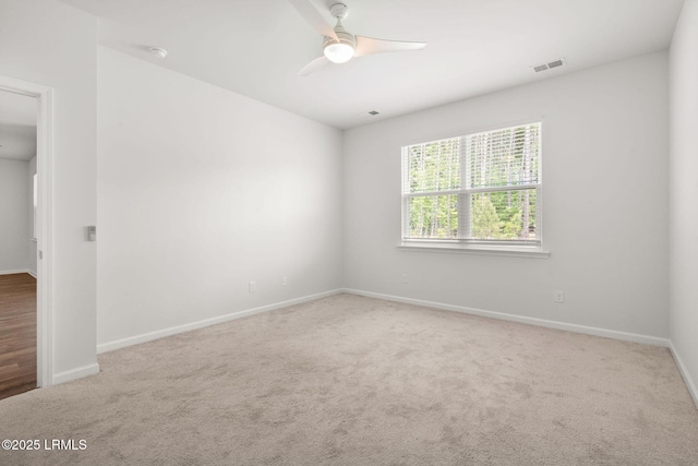 spare room featuring carpet floors, ceiling fan, visible vents, and baseboards