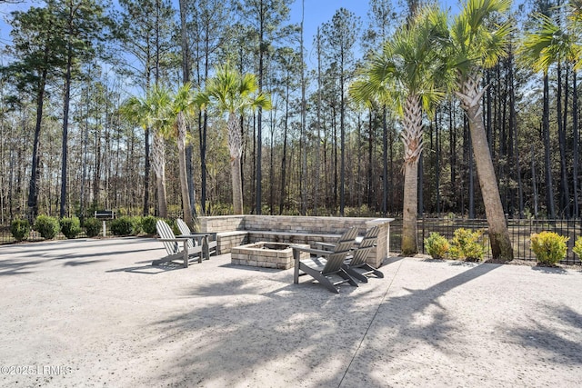 view of patio / terrace featuring a view of trees, fence, and an outdoor fire pit