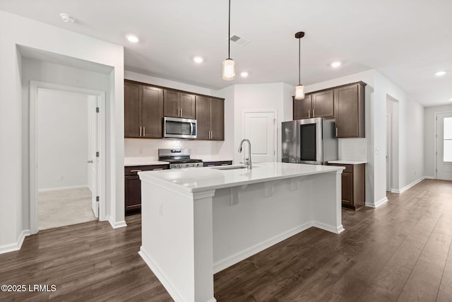 kitchen with a sink, dark brown cabinetry, stainless steel appliances, and dark wood-type flooring