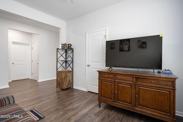 sitting room with dark wood-type flooring and baseboards