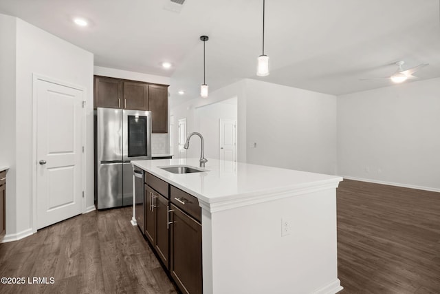 kitchen featuring dark brown cabinets, a sink, light countertops, dark wood-style floors, and stainless steel appliances