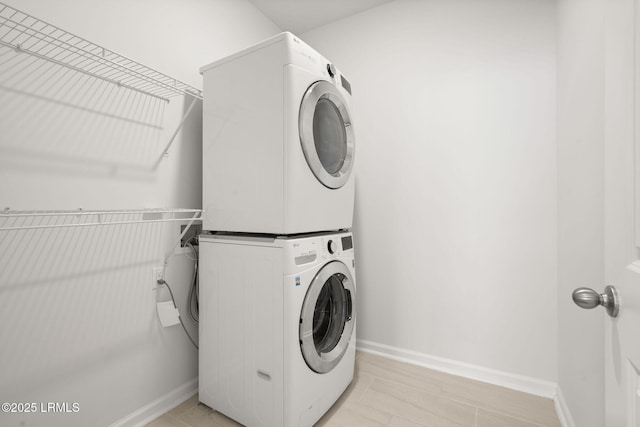 laundry area featuring laundry area, baseboards, and stacked washing maching and dryer