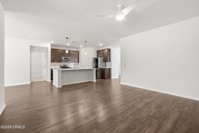 unfurnished living room with ceiling fan, a sink, recessed lighting, baseboards, and dark wood-style floors