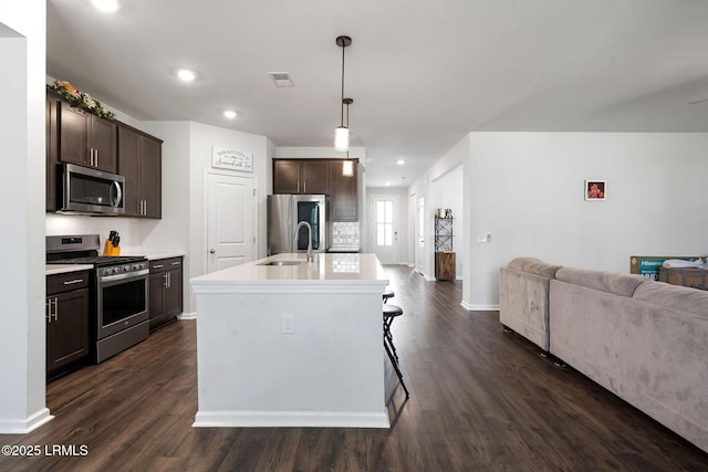 kitchen featuring dark brown cabinets, open floor plan, appliances with stainless steel finishes, and a sink