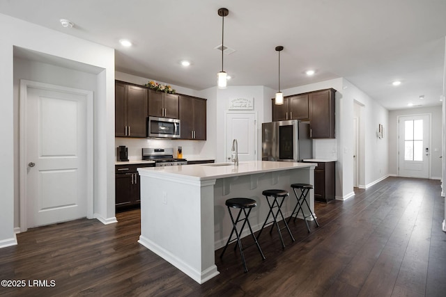 kitchen with dark brown cabinets, visible vents, dark wood-style flooring, and stainless steel appliances