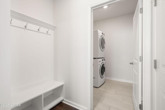 laundry area with laundry area, baseboards, and stacked washer / drying machine